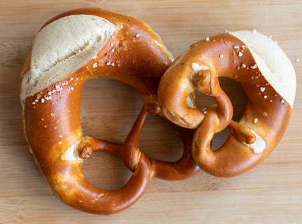 Two pretzels, one craft. Tradition served on a wooden board. A small and a normal pretzel from a