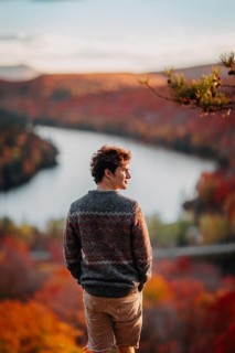 A man stands overlooking a vibrant autumn landscape in Quebec, Canada, as the foliage turns