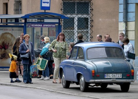 Krakow, POL, 02.05.2004 - Passengers wait for a bus at a bus stop in Krakow where an old car is