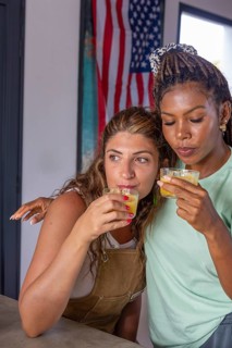 Two women share a warm embrace while enjoying a drink, symbolizing the strength and love within a