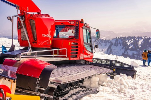 Red snowcat in snowy mountain area with views of the countryside, Hochgrat Mountains, Allgäu Alps,