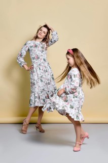 Beautiful mom and daughter in identical dresses dancing in studio