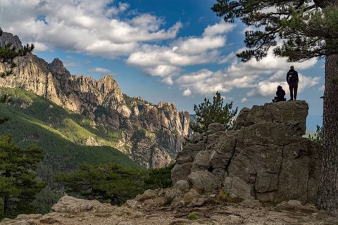 Tourists look out at the Bavella Needles mountain range or Aiguilles de Bavella, Corsica, France