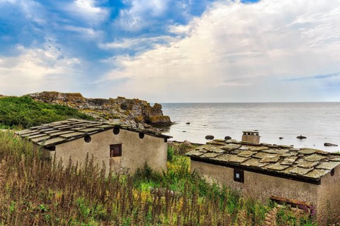 Historic fishing huts, beach huts with typical stone slabs on the roofs, rocky coast, barren