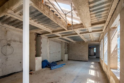 A spacious interior construction site featuring exposed metal framework and unfinished walls.