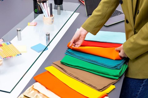 A professional image consultant arranges vibrant fabric swatches on a table, preparing for a