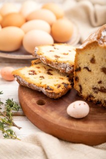 Homemade easter pie with raisins and eggs on plate on a white wooden background and linen textile.