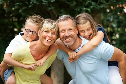 A happy family in the park, four people, man, woman, girl, boy, 8, 9, 35, 45 years piggyback,