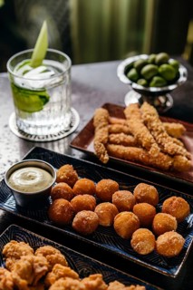 A variety of tapas featuring fried shrimp and golden-brown bites, complemented by a refreshing