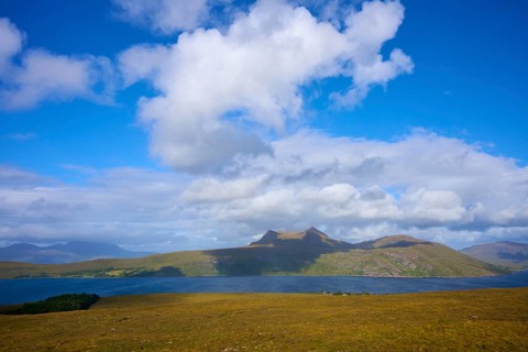 Sunlit mountains and lake under a slightly cloudy blue sky, Little Loch Broom, view point,