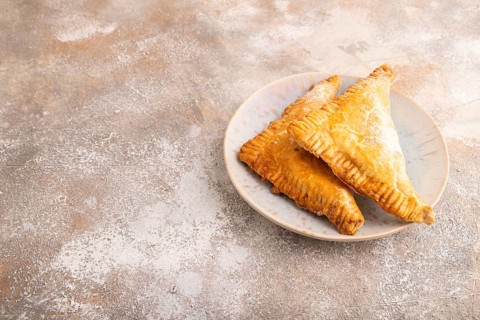 Triangles Pie, Puff Pastry, Samsa with cherry jam on brown concrete background, side view, copy