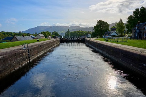 A quiet canal with lock surrounded by green spaces and clear skies, Caledonian Canal, Fort