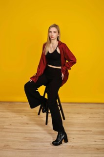 A model showcases a fashionable look, sitting on a black stool with one leg stretched. She wears a