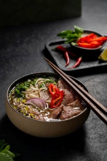 Traditional Vietnamese beef pho served in a bowl, featuring slices of beef, noodles, red onions,