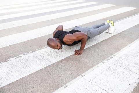 A fitness cuban man performs push ups on a city crosswalk, showcasing strength and dedication.