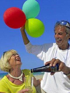 Seniors, couple on the beach in Ibiza, balloons, champagne, celebration, holiday joys
