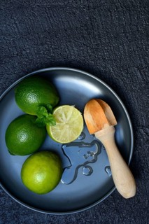 Limes with citrus squeezer on plate, halved