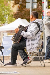 Man playing accordion outdoors while people walk by, Sindelfingen, Böblingen district, Germany