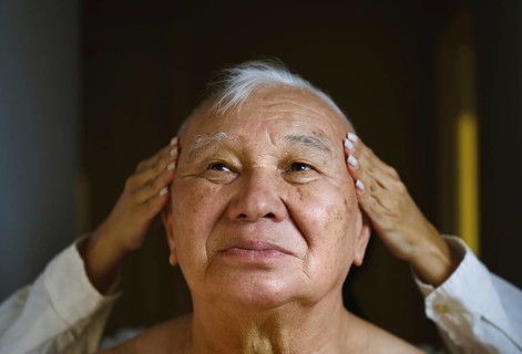 An elderly Asian man enjoys a soothing head massage His serene expression highlights a moment of