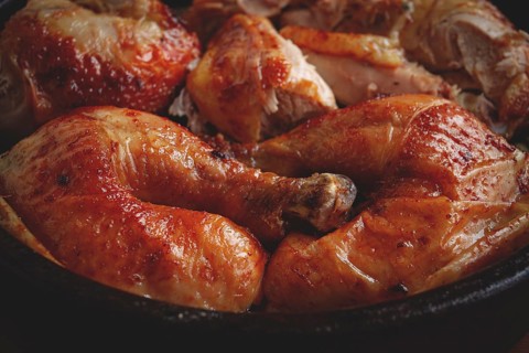 Grilled chicken pieces in a frying pan, wooden background, top view, homemade, no people