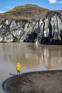 Tourist at the lakeside of a glacier lagoon, glacier tongue with crevasses and lake,