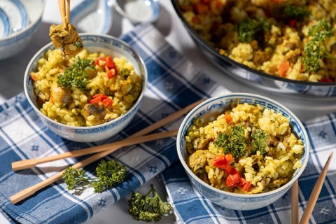 Dishes of fried rice and chopsticks next to the pan, decorated with parsley