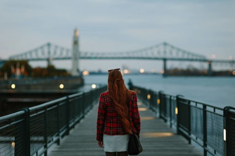Back view of unrecognizable woman with red hair walking on a boardwalk in Montreal during fall,