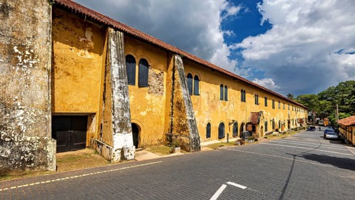 Long, old building with yellow façade and historic features under a cloudy sky, The historic