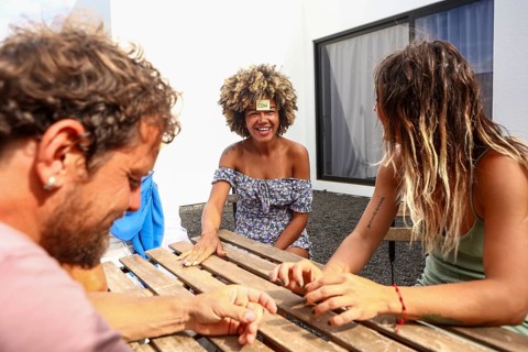 A multiethnic group of friends laughing and enjoying a guessing game outside Bright day, casual
