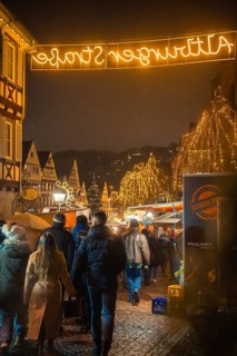 Festive Christmas market in the old town at night with illuminated trees and many visitors,