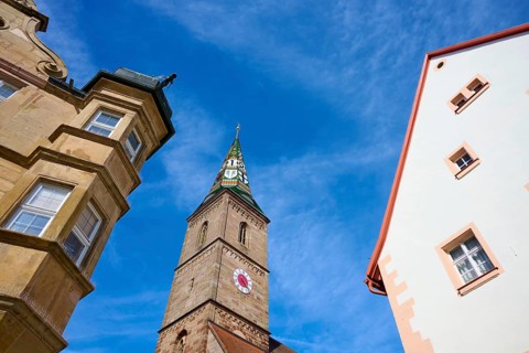 View of a church tower and surrounding historic buildings under a clear blue sky,