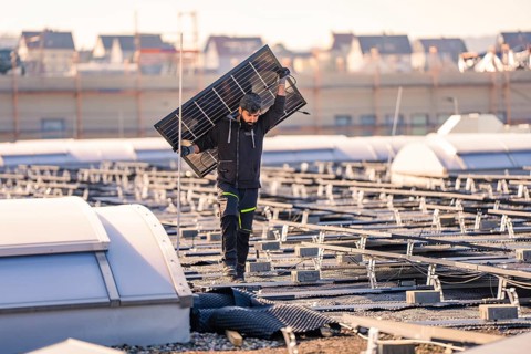Worker with solar panel on a roof, clear conditions, protective clothing, PV installation at OBI