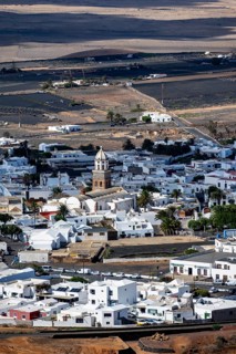 View of town, white houses of Teguise with church tower in dry volcanic landscape, Lanzarote,