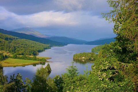 The sun's rays hit a river flanked by wooded hills, Queens View, Fincastle, Pitlochry, Scotland,