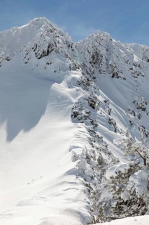A breathtaking view of a snowy mountain under a clear blue sky, with dramatic snow-covered peaks