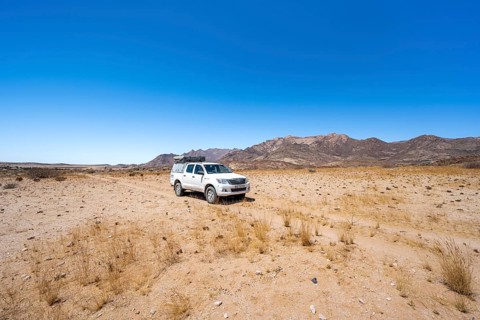 Toyota Hilux off-road vehicle on a sandy track, desert landscape with Brandberg, Erongo,