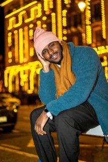 Vertical portrait of a cool african man posing sitting in the city in a Christmas night