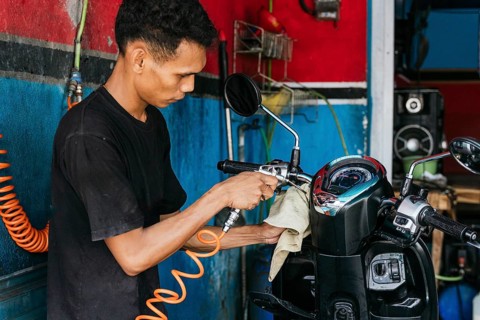 A skilled motorcycle cleaner uses specialized tools to meticulously clean and polish a motorcycle