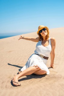 Vertical photo of a woman showing an idyllic coastal landscape sitting on the sand in Cabo de Gata,