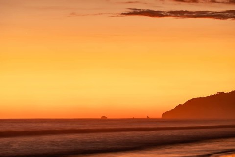 After sunset, the deep red sky glows above palms and ocean spray with views of Corcovado National