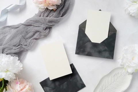 A sophisticated wedding stationery layout featuring elegant dark envelopes, blank cards, delicate