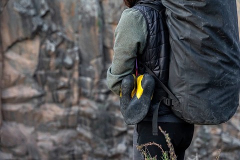 A climber prepares for a traditional climbing adventure in nature, carrying essential gear