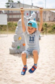 6-7 old boy hangs on the exercise bar in the playground