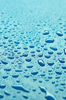 A detailed close up of water droplets on a smooth blue surface, showcasing the clarity and diverse