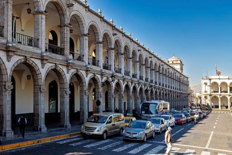 Buildings with arcades, cars and pedestrians on the street. Historic architecture in sunshine, The