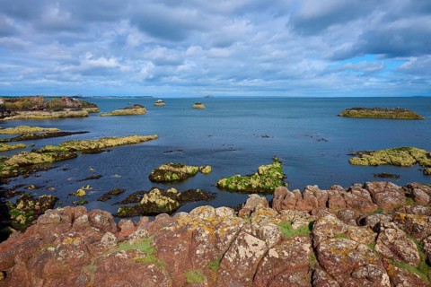 A rugged rocky coastline overlooking the sea under a cloudy sky, Dunbar, East Lothian, Scotland,