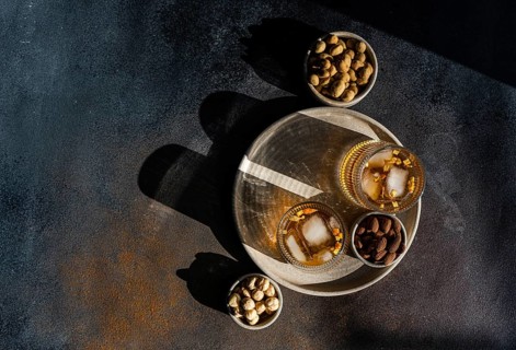 Top view of spiced cognac based cocktails with cinnamon and star anise, accompanied by bowls of