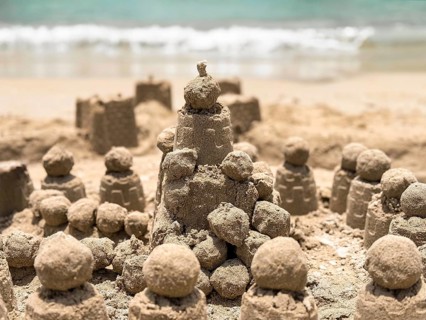 A picturesque scene of detailed sand castles crafted by the seaside, with waves gently lapping in