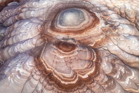 Aerial capture of stunning bentonite sandstone formations in Utah. The layered textures and earthy