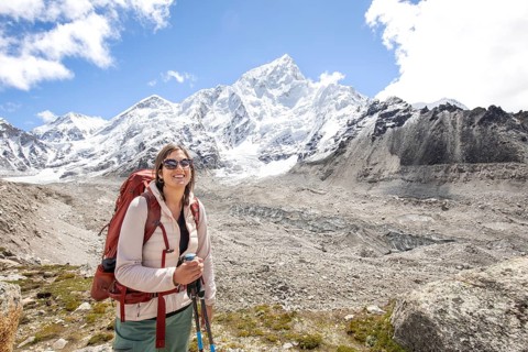 A woman in outdoor gear enjoys a trekking adventure near Mount Everest, surrounded by stunning